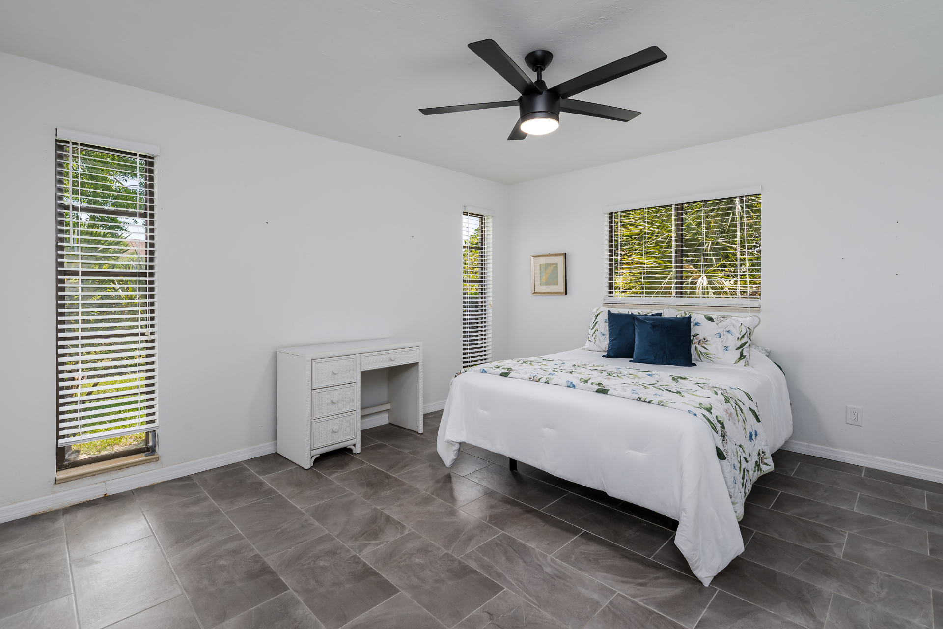 Bright guest bedroom with tile floors and garden views